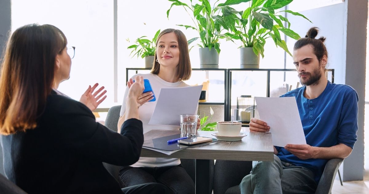 Couple discussing paperwork with real estate agent at a table at a coffee shop