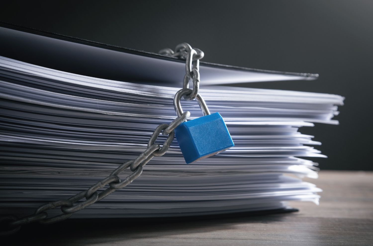 Padlock and chain protecting stack of papers and files
