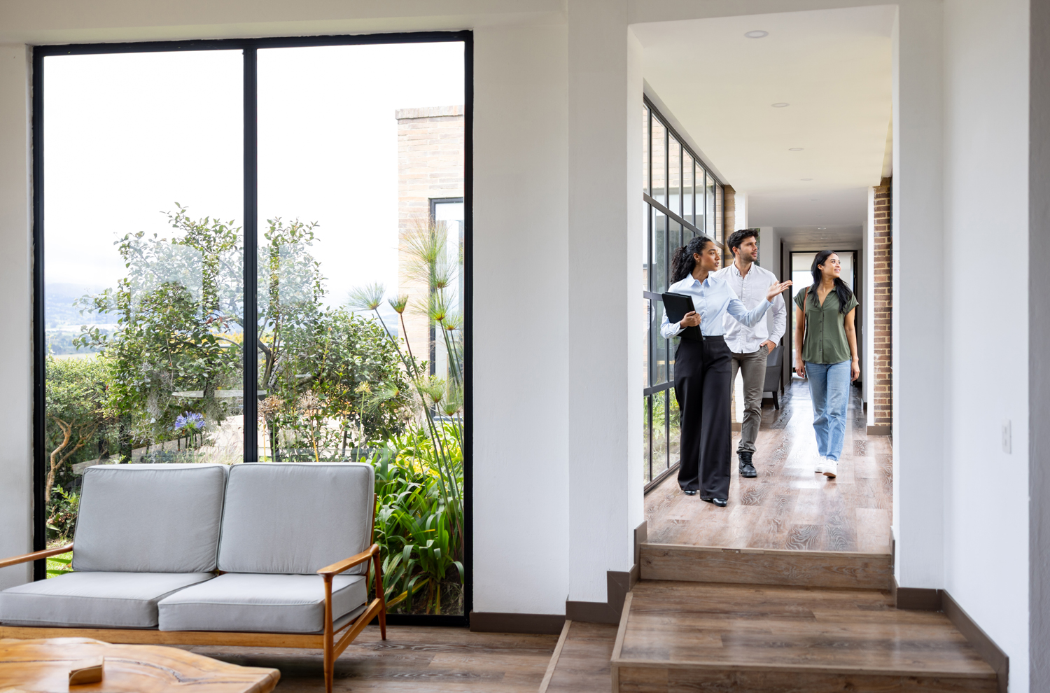 Female realtor walking through hallway in home with potential buyers