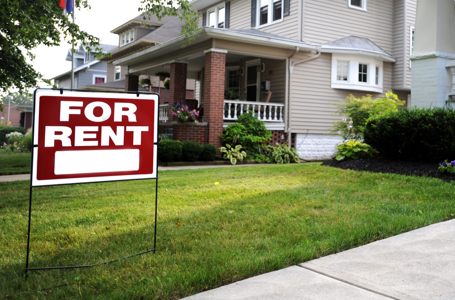 For rent sign in front yard with house in background