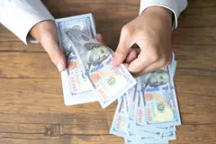 Aerial view of businessman hands counting U.S. dollar bills over desk